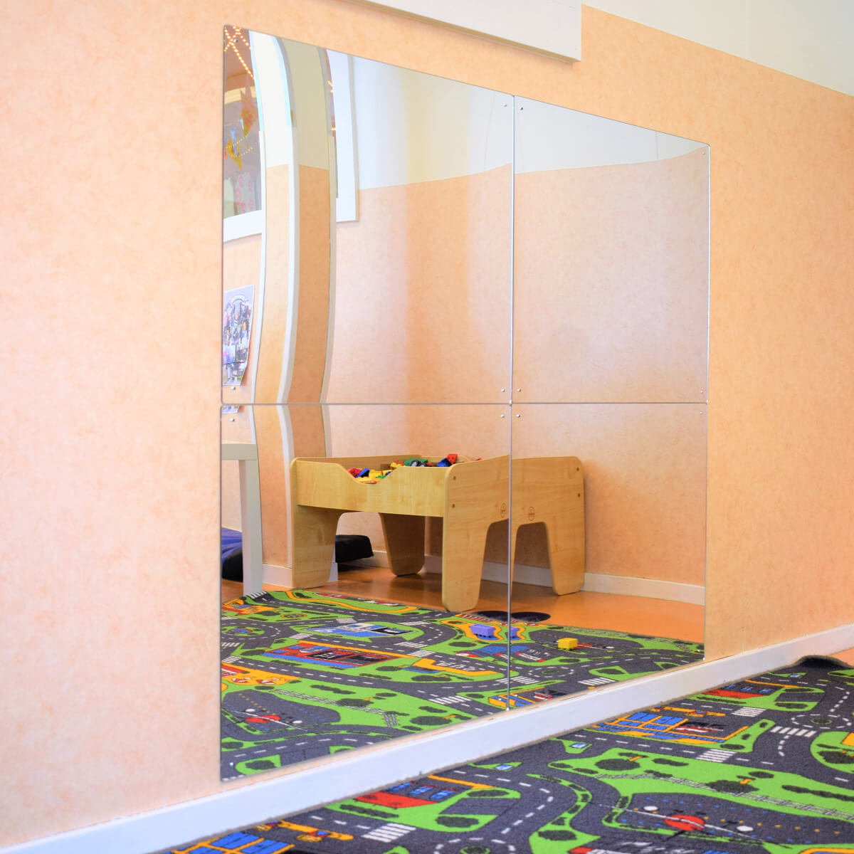 Mirrored wall reflecting colorful playroom and carpet.