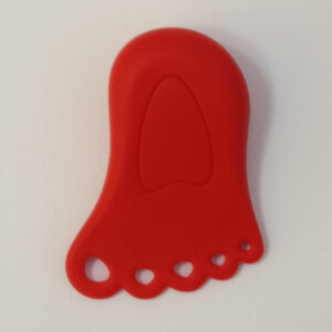 Red foot-shaped doorstop lies on white surface.